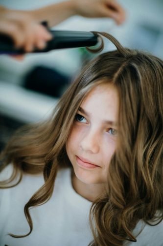 Close-up of a girl getting her hair curled at a salon, showcasing professional hairstyling.